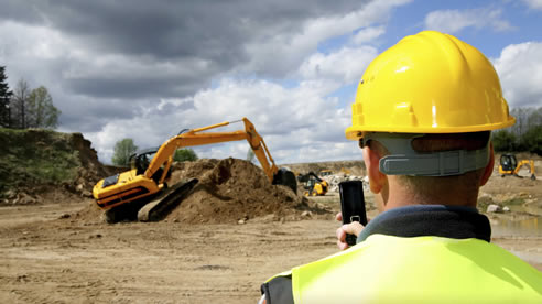 man in construction hat with mobile device onsite